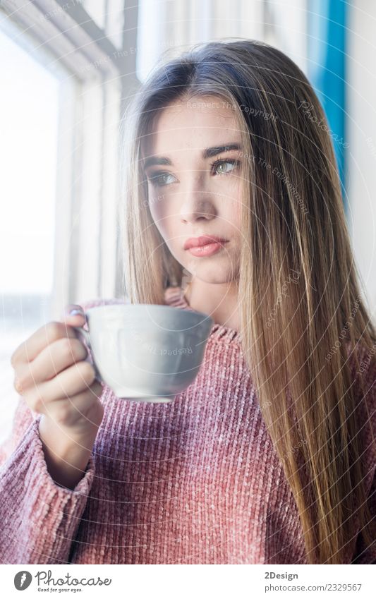 Nachdenkliche Frau, die durch ein Fenster schaut. Heißgetränk Tee Lifestyle schön Gesicht Erholung ruhig Meditation Winter Haus Mensch Erwachsene Wetter Regen