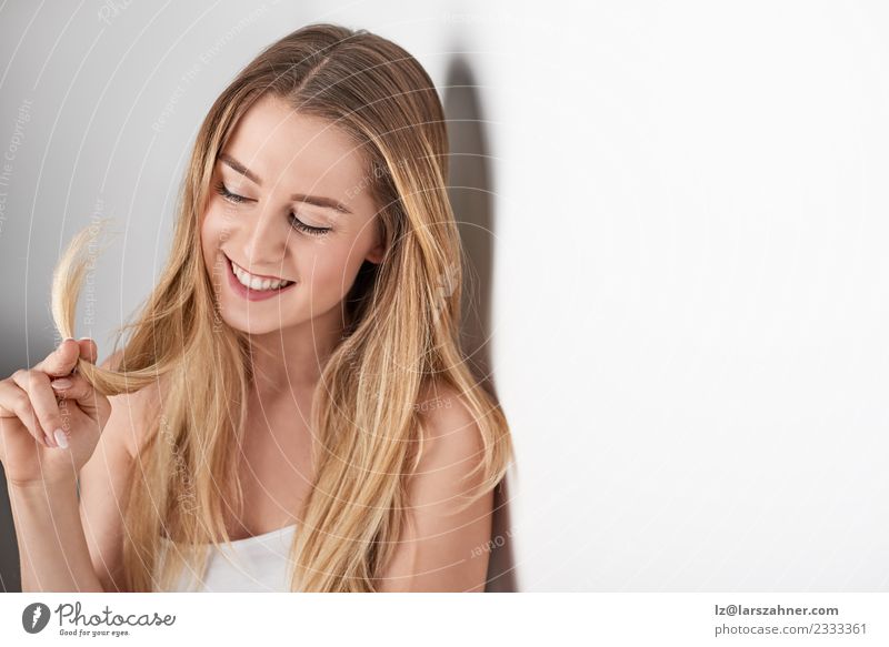 Junge lächelnde blonde Frau, die sich gegen eine Wand lehnt. Lifestyle Glück schön Gesicht Behandlung Erwachsene 1 Mensch 18-30 Jahre Jugendliche glänzend