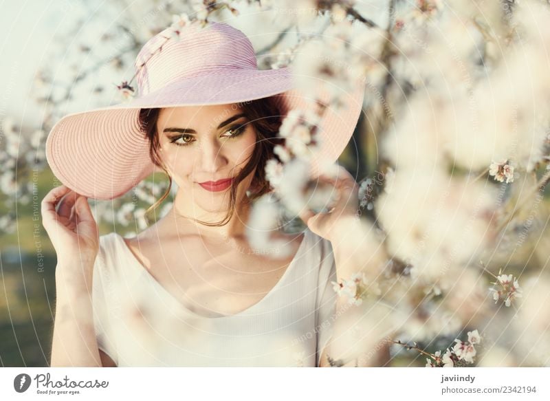 Junge Frau zwischen den Mandeln blüht im Frühling. Stil schön Gesicht Mensch feminin Jugendliche Erwachsene 1 18-30 Jahre Blume Mode Kleid Hut brünett rosa weiß