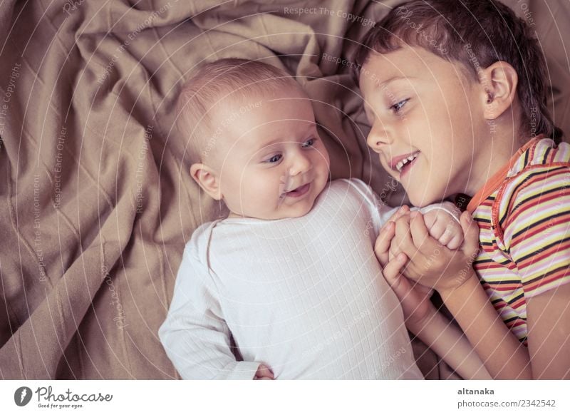 kleiner Junge spielt mit Neugeborenen auf dem Bett am Tag Freude Glück Spielen Schlafzimmer Kind Baby Kleinkind Familie & Verwandtschaft Freundschaft Kindheit