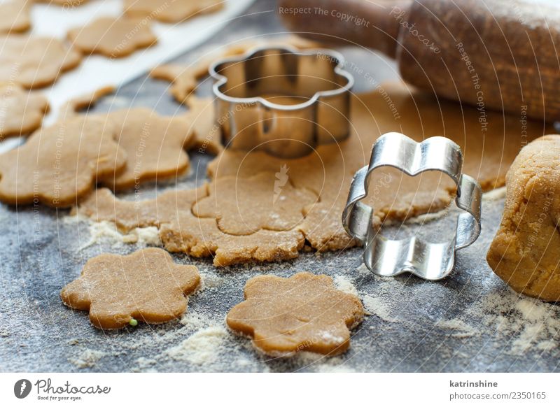 Kekse mit Keksausstechern auf einem dunklen Tisch zubereiten. Teigwaren Backwaren Dessert Küche Blume Metall machen braun Tradition backen Bäckerei Biskuit