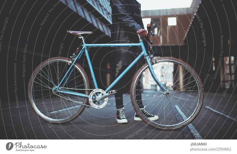 Junger Mann hält blaues Fahrrad in der Stadt. modern Stadtleben Großstadt Schlittschuhlaufen Lifestyle Hipster Schickimicki Mode Bekleidung Jacke erwärmen
