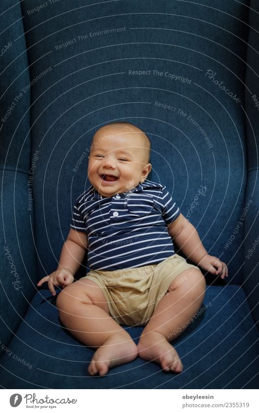 ein glücklicher kleiner Junge, der auf einem Sofa sitzt und lächelt. Lifestyle Freude Glück schön Freizeit & Hobby Wohnzimmer Kind Mensch Baby Kleinkind