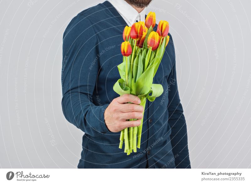 Mann mit Bart, der einen Blumenstrauß aus Tulpen hält. Glück schön Flirten Feste & Feiern Valentinstag Mensch Erwachsene Mutter Hand Vollbart Liebe blau gelb