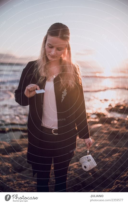 Junge Frau schaut sich das Polaroidbild am Strand an. Abenddämmerung Gefühle Glück Leben Lifestyle Spanien Sommer Sonne Sonnenuntergang Wärme Abenteuer