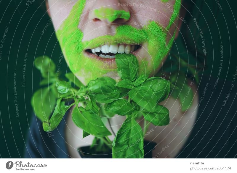Junge Frau beißt auf ein Basilikumblatt. Lebensmittel Gemüse Ernährung Essen Bioprodukte Vegetarische Ernährung Stil Design exotisch Haut Gesicht Mensch feminin