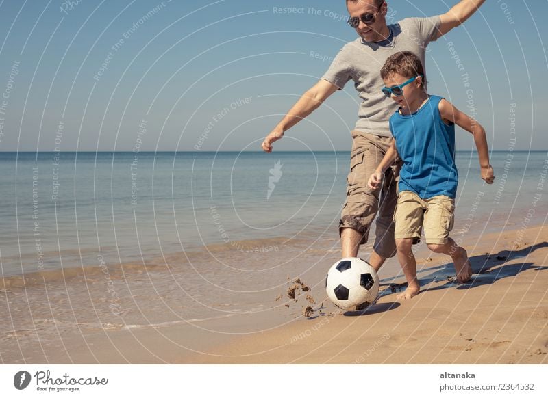 Vater und Sohn spielen Fußball am Strand am Tag. Konzept der freundlichen Familie. Lifestyle Freude Glück Leben Erholung Spielen Ferien & Urlaub & Reisen