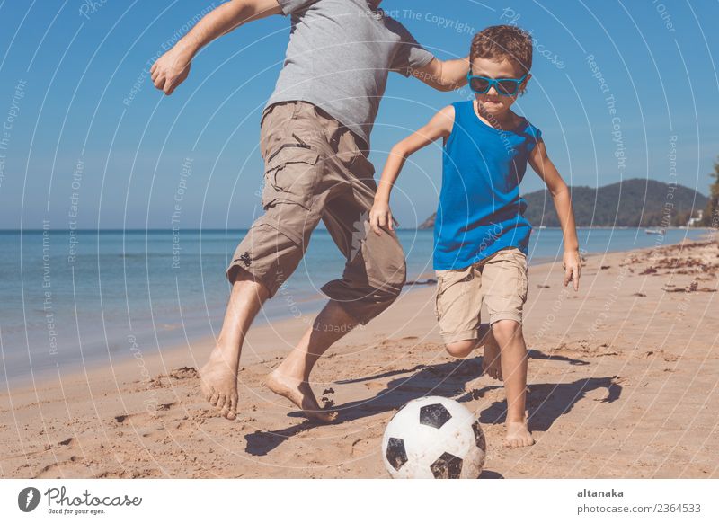 Vater und Sohn spielen Fußball am Strand am Tag. Konzept der freundlichen Familie. Lifestyle Freude Glück Leben Erholung Spielen Ferien & Urlaub & Reisen