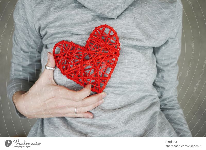 Junge Frau hält ein rotes Herz an ihrer Brust. Design Gesundheit Gesundheitswesen Wellness Leben Valentinstag Muttertag Mensch feminin Jugendliche Erwachsene 1