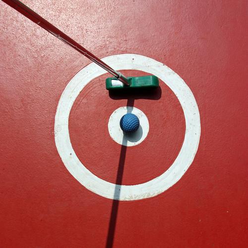 Eine ruhige Kugel schieben Minigolf Ausflug Ballsport Golfball Minigolfschläger Sportstätten Sonnenlicht rund rot Spielen Abschlag Punkt Kreis Farbfoto