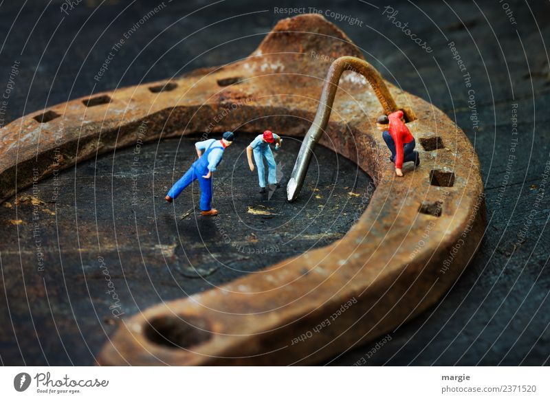 Miniwelten: kleine Männchen wundern sich über einem krummen Nagel auf einem Hufeisen Team Loch Schmied Tierschutz Miniatur Figur Eisen Glück Rost Hufschmied