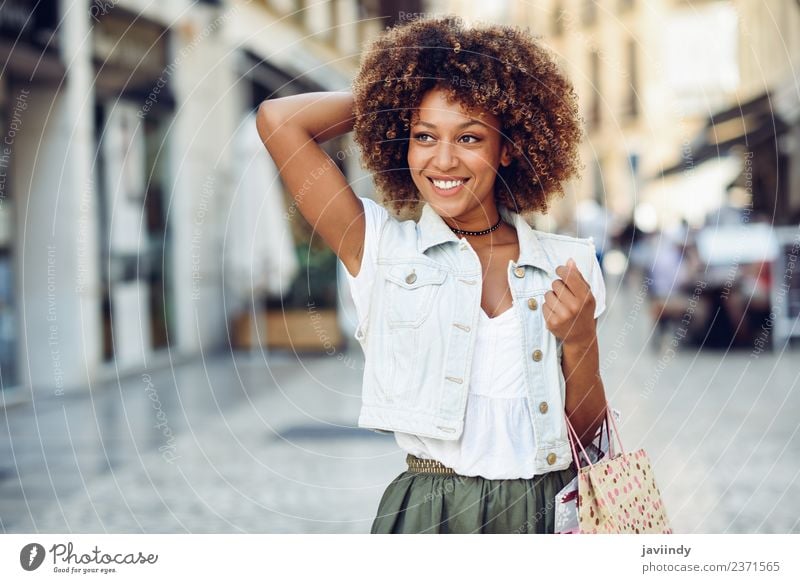 Junge schwarze Frau, Afrofrisur, mit Einkaufstüten auf der Straße. Lifestyle kaufen Stil Glück schön Haare & Frisuren Mensch feminin Junge Frau Jugendliche