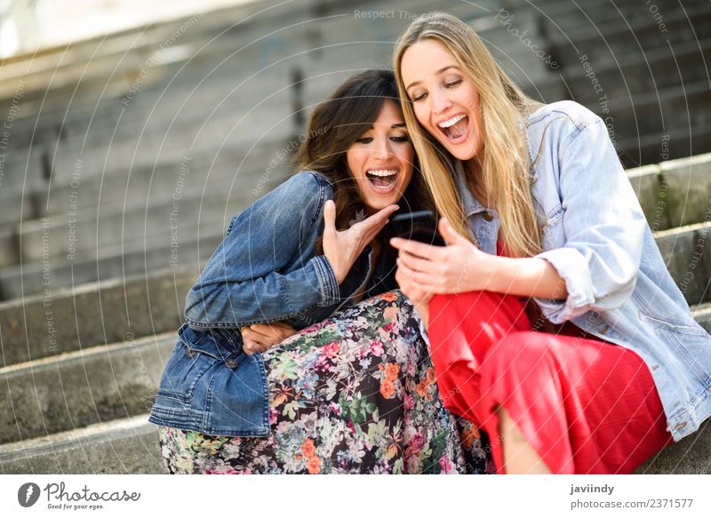 Zwei junge Frauen, die sich lustige Dinge auf dem Smartphone ansehen. Lifestyle kaufen Freude Glück schön Telefon Technik & Technologie feminin Erwachsene