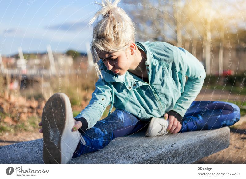 blonde Frau, die im Gras sitzt und sich in einem Park ausstreckt. Lifestyle Glück schön Körper Sport Mensch feminin Junge Frau Jugendliche Erwachsene 1