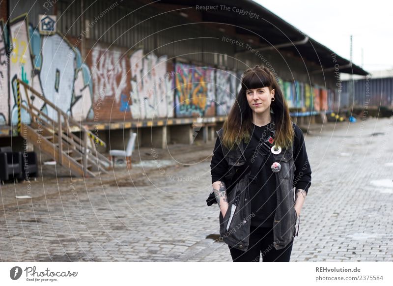 junge Frau steht auf einem alten Industriegelände mit Graffitis Junge Frau Blick in die Kamera Cool hip Typ Charakter Hamburg 18-30 Jahre Haare & Frisuren