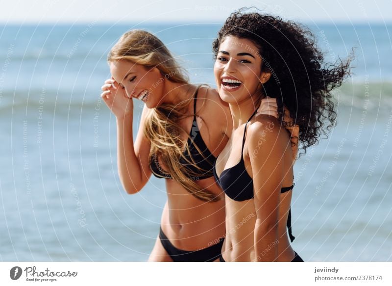 Lächelnde Frauen im schwarzen Bikini, die am Ufer entlang laufen. Lifestyle Freude Haare & Frisuren Ferien & Urlaub & Reisen Tourismus Sommer Strand Meer Mensch
