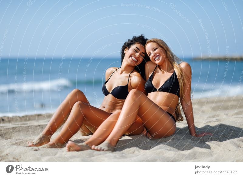 Zwei Frauen im Bikini, die auf einem tropischen Strandsand sitzen. Lifestyle Freude schön Körper Freizeit & Hobby Ferien & Urlaub & Reisen Tourismus Sommer Meer