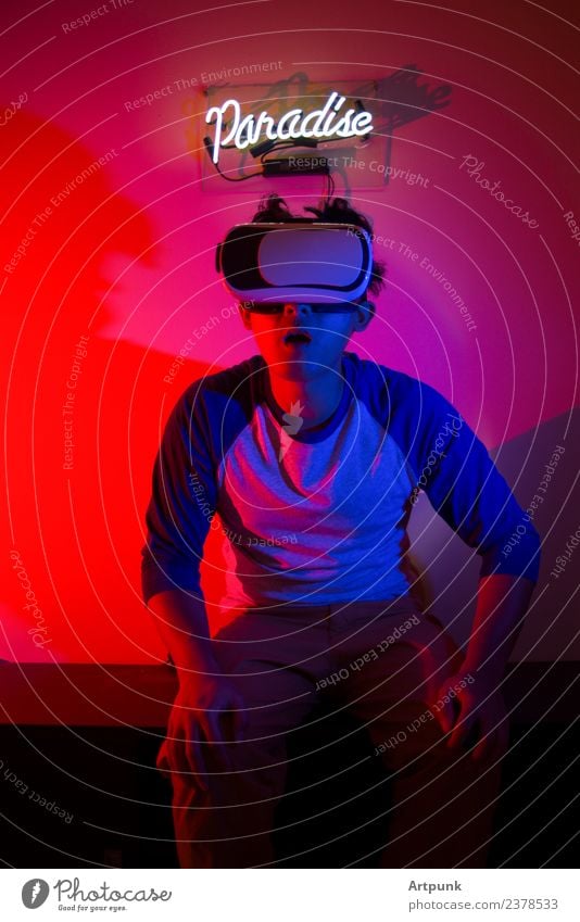 Ein junger Mann, der eine VR-Erfahrung genießt. Paradies virtuell Neonlicht neonfarbig Hinweisschild rot blau blitzen Gel Headset Technik & Technologie Computer