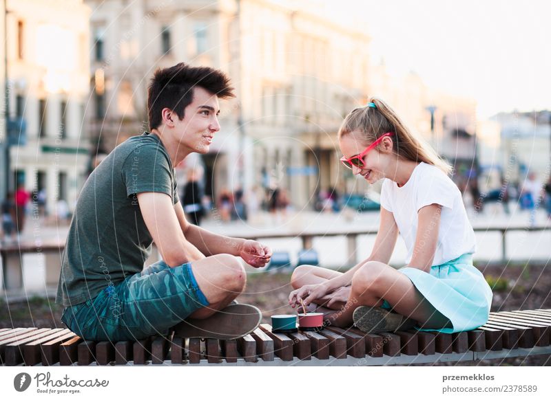 Junge Teenager-Mädchen und Junge verbringen Zeit zusammen in der Innenstadt genießen Eis an einem Sommertag zu essen. Verbringen Qualität Zeit auf sonnigen Nachmittag essen süßen Nachtisch. Downtown Bereich in den Hintergrund