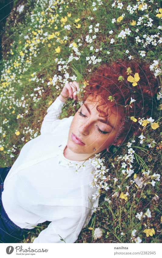 Junge rothaarige Frau, die in einem Blumenfeld schläft. Lifestyle elegant schön Haare & Frisuren Haut Gesicht Gesundheit Wellness harmonisch Wohlgefühl