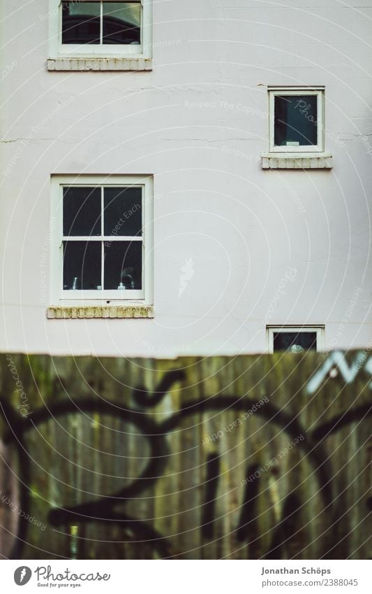 Fassade mit Holzwand in Brighton, England Stadt Stadtrand bevölkert Haus Armut hässlich Architektur Fenster Zaun Holzzaun Graffiti weiß trüb graphisch einfach