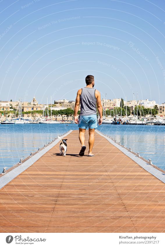 Ein Mann mit einem Hund, der auf dem schwimmenden Pier läuft. Glück Ferien & Urlaub & Reisen Sommer Sonne Meer Erwachsene Freundschaft Natur Himmel Herbst Küste