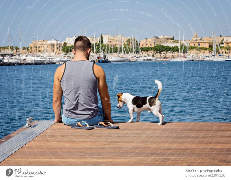 Ein Mann mit einem Hund, der auf dem schwimmenden Pier läuft. Glück Ferien & Urlaub & Reisen Sommer Sonne Meer Erwachsene Freundschaft Natur Himmel Herbst Küste