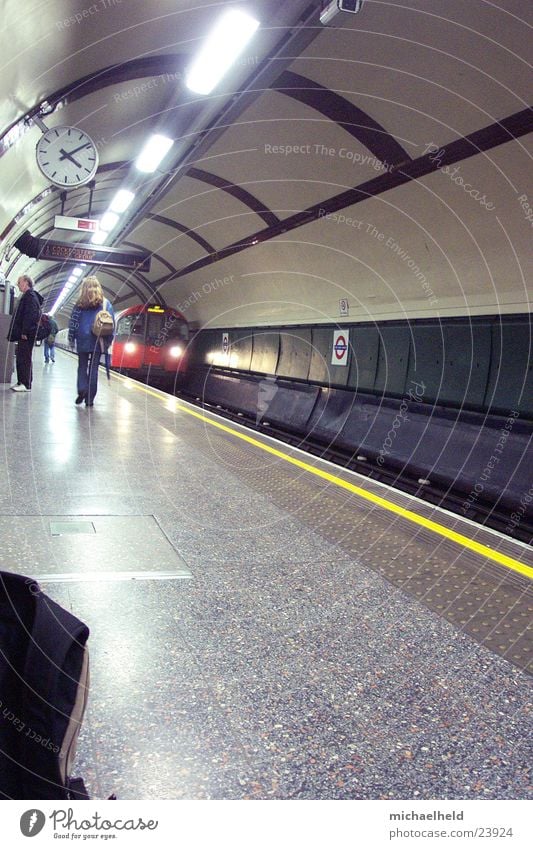 London Underground 3 U-Bahn Bahnsteig Neonlicht Licht Uhr unterwegs Verkehr einfahrender Zug Mensch Platform Passagier
