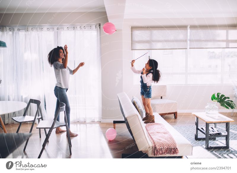 afrikanische Mutter und Tochter beim Spielen mit dem Ballon im Wohnzimmer Glück Dekoration & Verzierung Kind Frau Erwachsene Familie & Verwandtschaft Kindheit