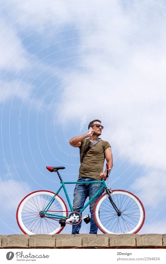 Junger Mann steht im Freien und ruft am Telefon an. Lifestyle Stil Ferien & Urlaub & Reisen Fahrradfahren Business sprechen Technik & Technologie Mensch