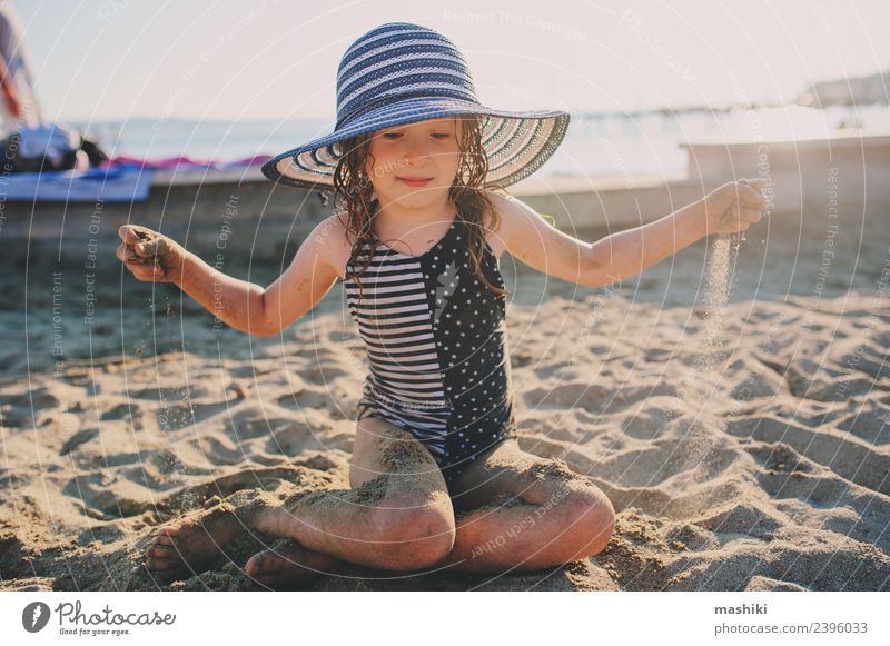 fröhliches Kind zum Entspannen am Sommerstrand Lifestyle Freude Leben Ferien & Urlaub & Reisen Sonne Strand Kindheit Sand Wärme Küste Hut Streifen genießen