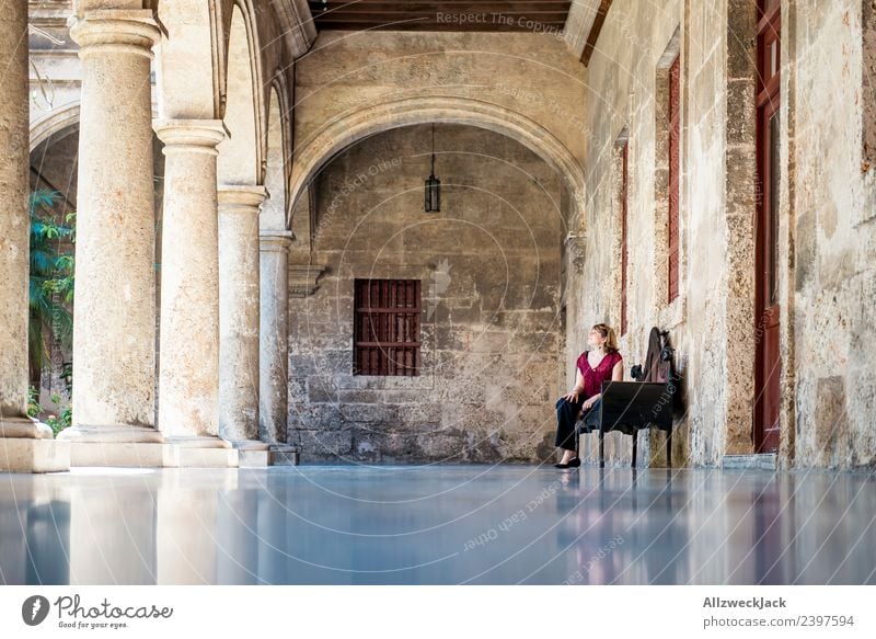 Junge Frau sitzt auf einer Bank im Hof eines alten Gebäudes Kuba Havanna Säule 1 Mensch sitzen Erholung Pause ausruhend genießen ruhig Mauer Reisefotografie