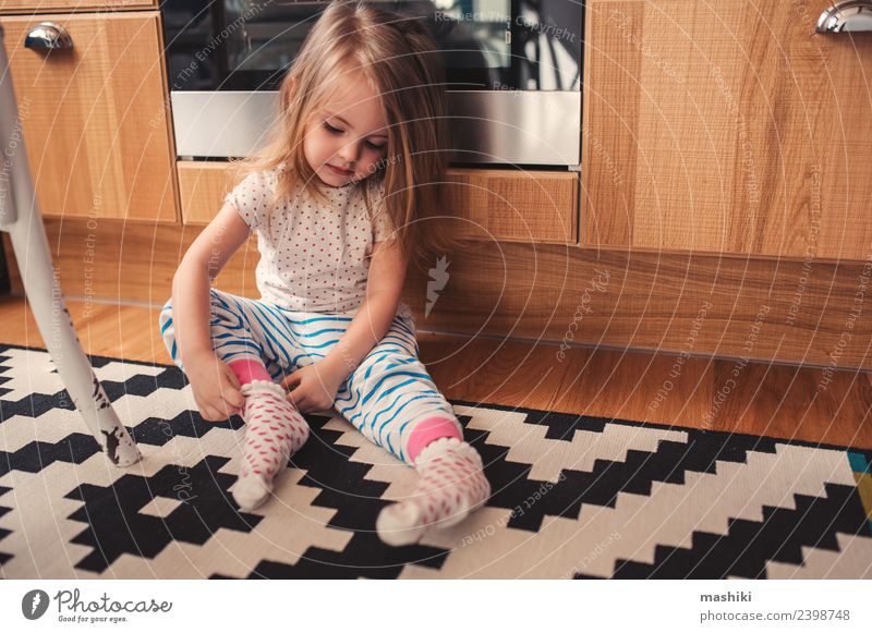 süßes Kleinkind Mädchen zieht zu Hause Socken an Frühstück Lifestyle Freude Glück schön Spielen Küche Kind Baby Frau Erwachsene Kindheit Bekleidung sitzen