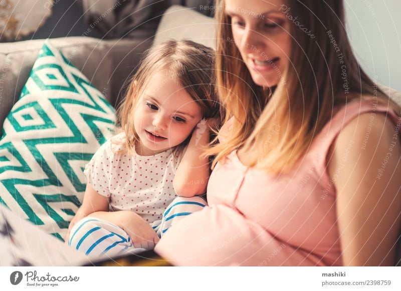 schwangere Mutter lesend Buch zu Kleinkind Tochter Freude Glück schön Spielen Sofa Kind Baby Eltern Erwachsene Schwester Familie & Verwandtschaft Lächeln lachen