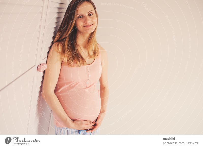 glückliche schwangere Frau zu Hause Lifestyle Glück schön Erwachsene Mutter Familie & Verwandtschaft Lächeln Fröhlichkeit rosa weiß reizvoll Babybauch Kaukasier