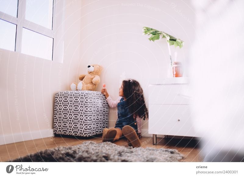 Afrikanisches Mädchen gibt Teddybonbons zu Hause. Glück schön Spielen Kind Stiefel Spielzeug Teddybär sitzen klein niedlich Bär heimwärts Raum Hintergrund