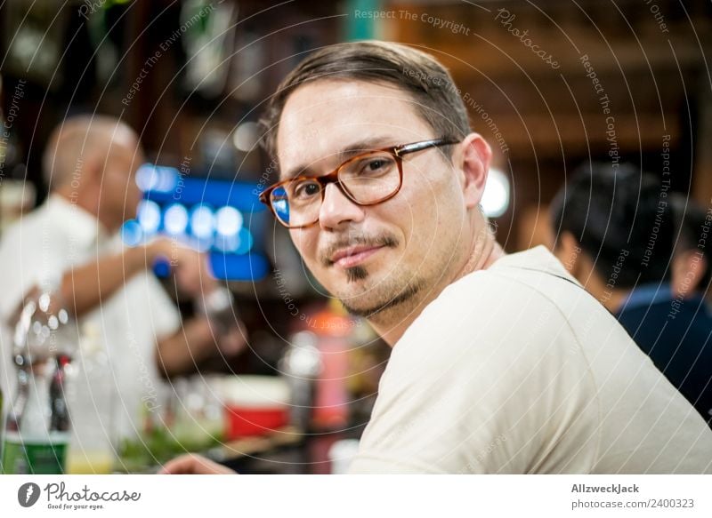 Portrait junger mann mit Brille an einer Bar Kuba Havanna Junger Mann Brillenträger Blick in die Kamera Zufriedenheit Lächeln Porträt Bart sitzen warten