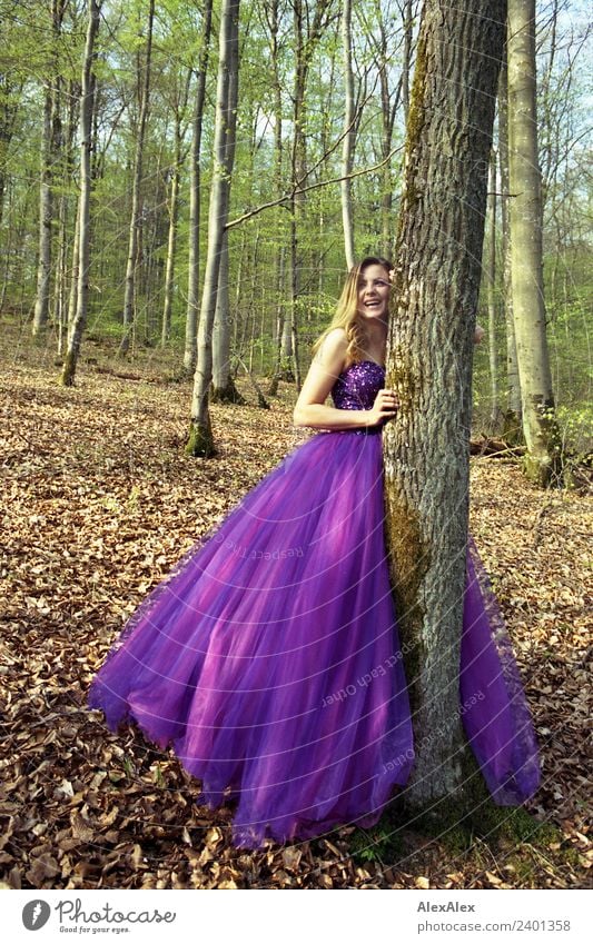 Junge, große, schöne Frau in einem lila Brautkleid lehnt sich im Wald an einen Baum und lacht Lifestyle elegant Stil Leben Junge Frau Jugendliche 18-30 Jahre