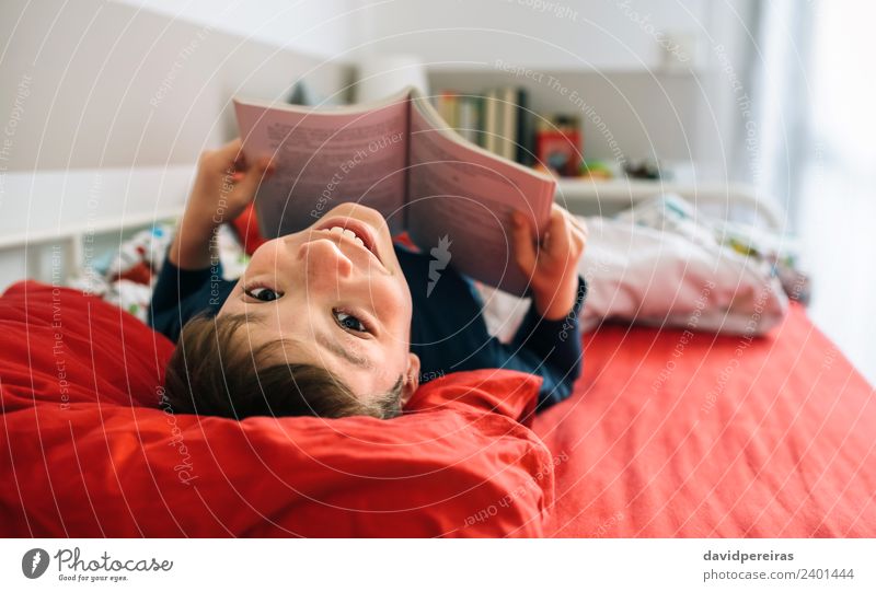 Junge, der auf dem Bett liegend ein Buch liest Lifestyle Freude Glück schön Windstille Freizeit & Hobby lesen Schlafzimmer Kind Mensch Mann Erwachsene Kultur