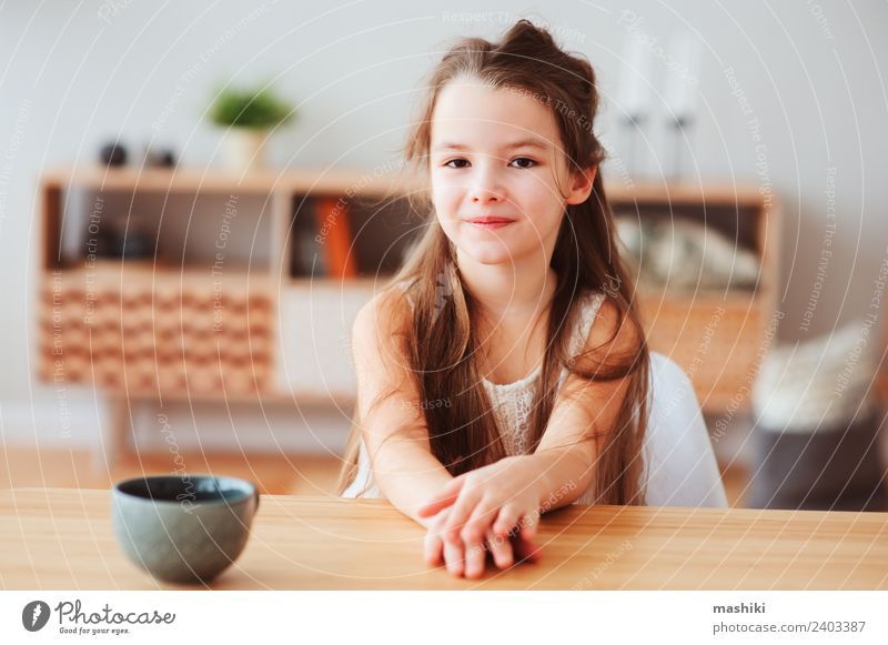 glückliches 5 Jahre altes Kind Mädchen beim Frühstücken Ernährung Kakao Tee Lifestyle Glück Tisch Küche Kindheit Lächeln sitzen authentisch heiß modern