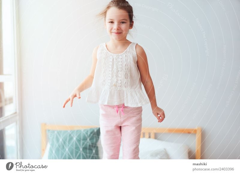 glückliches Kind Mädchen springt auf Bett Lifestyle Freude Glück Haare & Frisuren Erholung Sonne Schlafzimmer Spielzeug Teddybär Lächeln schlafen träumen klein