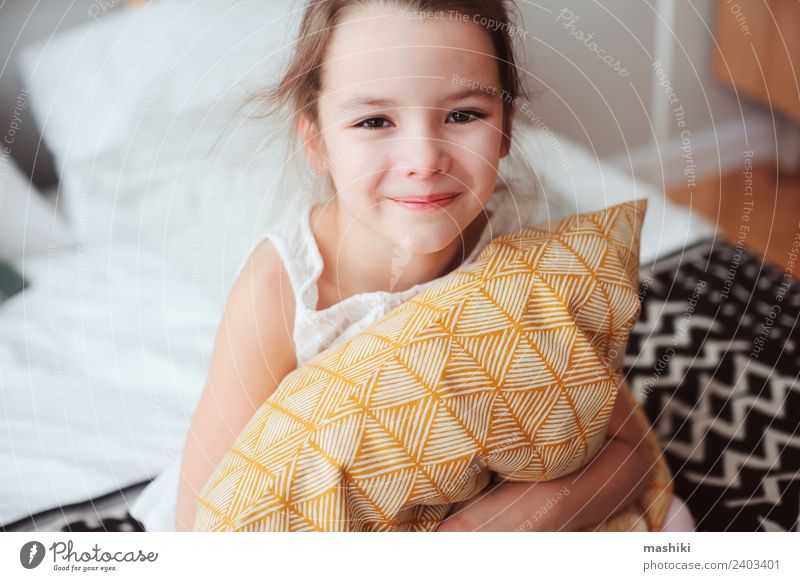 fröhliches Kind Mädchen sitzt auf dem Bett und umarmt Kissen Lifestyle Freude Erholung Sonne Schlafzimmer Spielzeug Teddybär Lächeln schlafen träumen klein