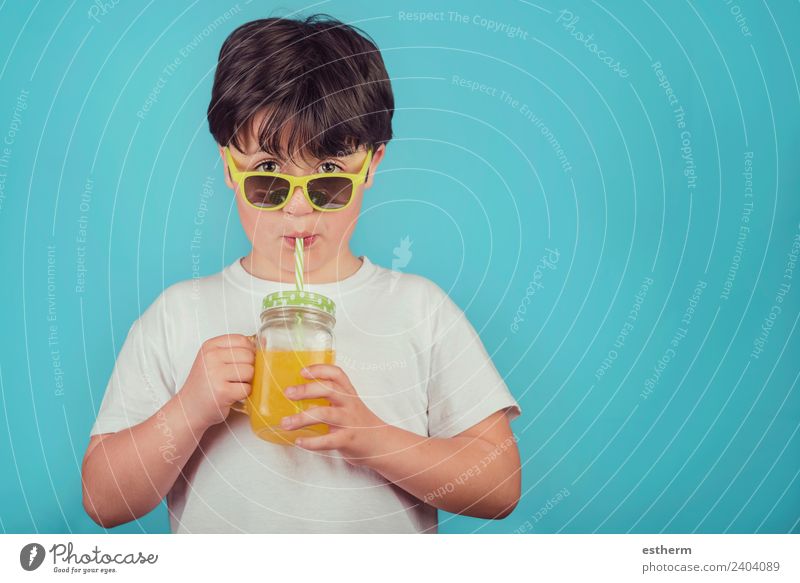glücklicher Junge trinkt Orangensaft auf blauem Hintergrund Dessert Ernährung Getränk trinken Limonade Saft Lifestyle Freude Wellness Leben Mensch maskulin Kind