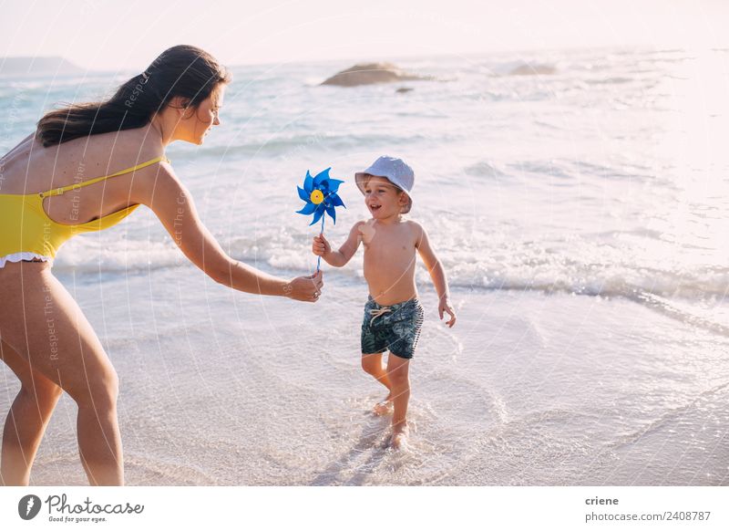 kaukasische Mutter und Sohn beim Spielen mit der Windmühle am Strand Lifestyle Freude Freizeit & Hobby Sommer Sonne Meer Kind Frau Erwachsene