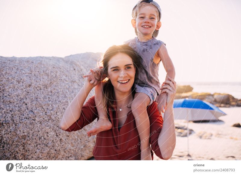 kaukasische Mutter, die ihren Sohn auf dem Rücken am Strand hat. Lifestyle Stil Freude Glück Spielen Sommer Sonne Kind Junge Frau Erwachsene