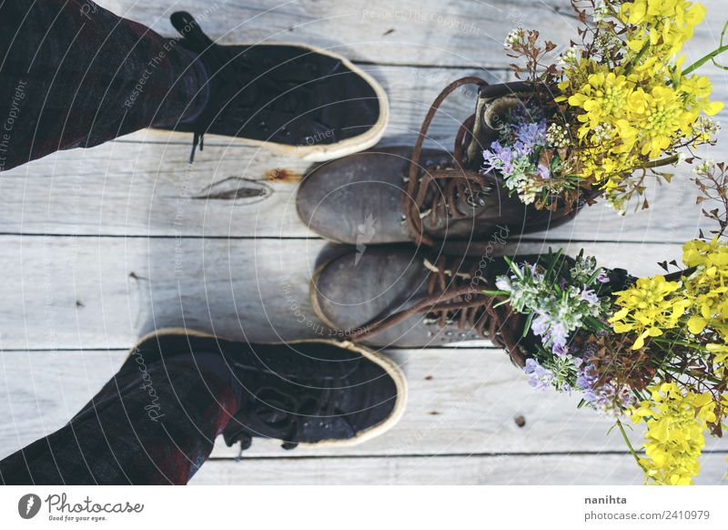Jemand steht vor alten Stiefeln voller Blumen. Lifestyle Stil Design Fuß Kunst Natur Pflanze Wildpflanze Topfpflanze Schuhe Turnschuh Holz Leder ästhetisch