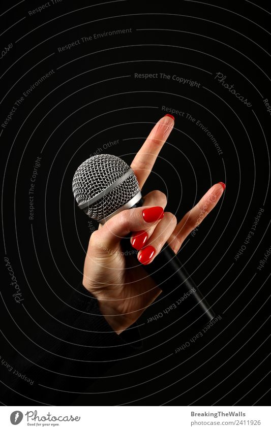 Damenhandmikrofon mit Teufelshörnern auf Schwarz feminin Junge Frau Jugendliche Erwachsene Hand Finger Punk Show Musik Konzert Bühne Sänger Musiker Medien rot