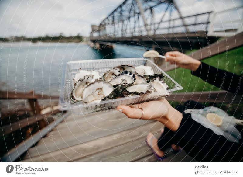 Austernschale in einer Frau Hand mit einem Fluss und einer Brücke im Hintergrund. Lebensmittel Meeresfrüchte Lifestyle Stil Ferien & Urlaub & Reisen Tourismus