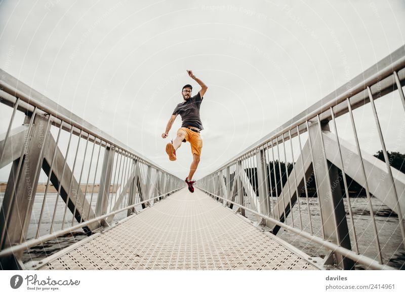 Weißer Mann mit Shorts und T-Shirt springt mit Energie auf eine Brücke. Lifestyle sportlich Wellness Leben Wohlgefühl Freizeit & Hobby Ferien & Urlaub & Reisen