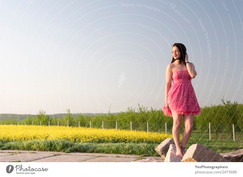 Frau in einem rosa Kleid bei Sonnenuntergang elegant schön ruhig Sommer Erwachsene Natur Wiese brünett Lächeln Fröhlichkeit gelb grün Lebensfreude Erholung